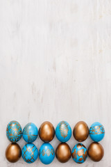 golden decorated easter eggs on white wooden background
