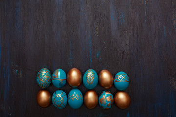 golden decorated easter eggs on dark wooden background