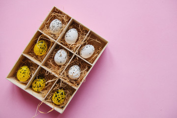 A set of eggs in a box or container on a pink background. Festive Easter concept in minimal style. Nearby there is a place for text.