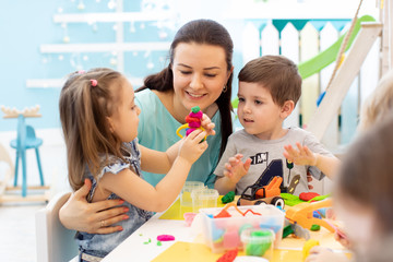 Teacher with kids working with plasticine at kindergarten or playschool