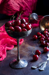 Old vase with cherries on the table