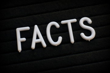 The word Facts in white plastic letters on a notice board