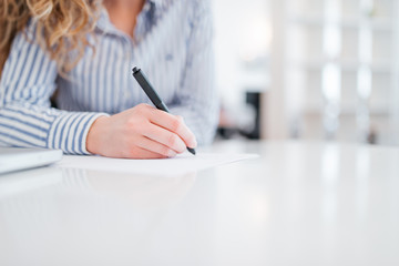 Businesswoman making a note, close-up, copy space.