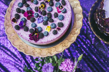 Obraz na płótnie Canvas Festive cake with violet sour cream on a metal plate stand.