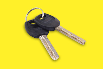 Pair of metal shiny keys with black plastic or rubber handle attached of keyring for door or car in center on yellow background. Real estate concept or open and close life
