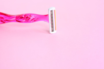 New disposable plastic razor with steel blade for daily safety personal shaving on pink neutral background with empty space for text. Pink plastic woman shave razor with selective focus. 