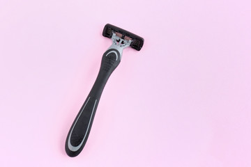 Man black and grey shaving razor with selective focus on neutral background. New disposable plastic razor with steel blade for daily safety personal shaving on pink background with empty space for tex