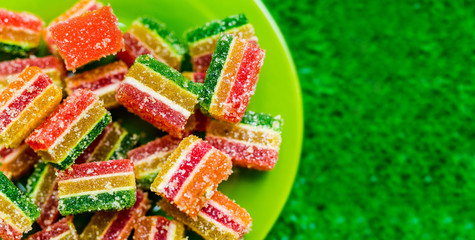 Colorful jelly candy on a green plate. Close up over blurred grass background