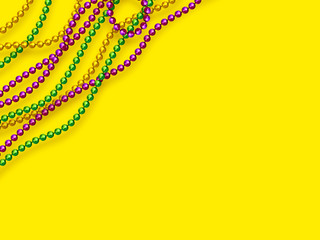 Mardi Gras beads in traditional colors. Decorative glossy realistic elements on yellow background. Copy space, top view. Vector illustration. © ludmila_m