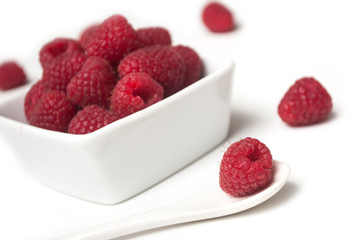 Closeup of raspberries in a white bowl on white background