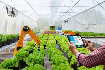 Farmer holding a tablet smart robotic harvest in agriculture futuristic robot automation to work technology increase efficiency