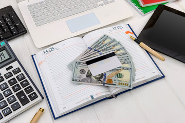 Obraz premium Dollars with laptop and diary top view