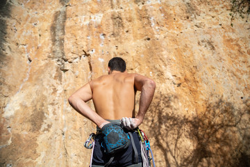 Climber man taking magnesium before climbing outdoors