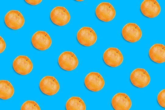 Diagonal rows of many fresh whole ripe mandarins on blue background