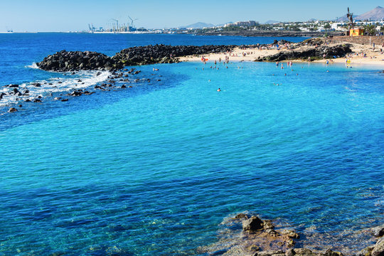 Lagoon with turquoise clear water in Playa Jablillo beach, in Costa Teguise, Lanzarote, Canary islands. Sandy beach with blue sea, volcanic rocks, selective focus