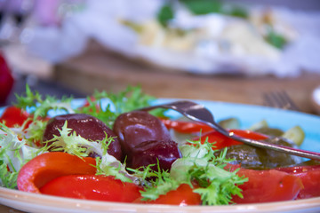 Vegetable slicing on a plate with pepper, parsley, dill, tomatoes and pickled plums
