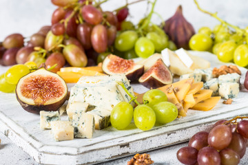 Cheese plate with grapes, figs and nuts. 