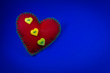 Handmade red stitched toy heart on blue background