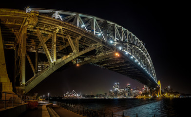 Fototapeta na wymiar East side of Sydney harbour bridge at nihgt with bright reflecting in the blurred waters of harbour