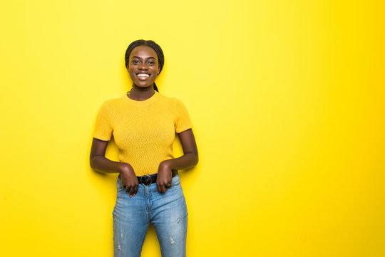 Beauty Portrait Of Young African American Girl Posing On Yellow Background, Looking At Camera, Smiling. Studio Shot.