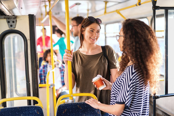 Two girls in a bus standing, chatting and smiling. © Dusan Petkovic