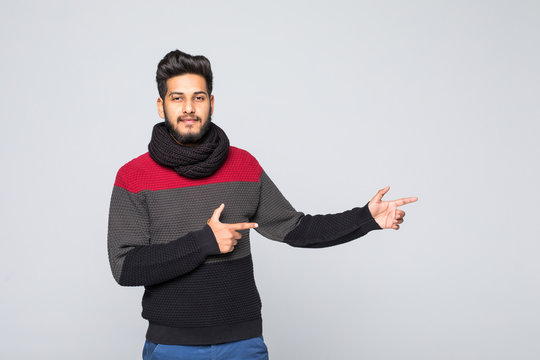 Young handsome arabic man wearing winter sweater over isolated gray background with a big smile on face, pointing with hand and finger to the side looking at the camera.