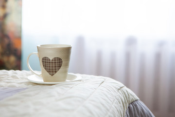 morning cup of coffee on the background of the bed and the window
