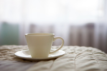 morning cup of coffee on the background of the bed and the window