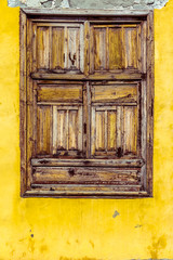 Verschlossenes Holzfenster an einem alten gelben Haus