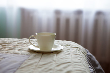 morning cup of coffee on the background of the bed and the window