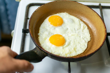 fry the eggs in a pan on the stove, holding the pan in your hand