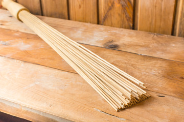Bamboo broom lies on a wooden bench in the sauna