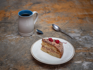 A sweet lunch of tea and a slice of homemade cake on an old rustic table.