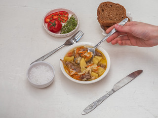 Lunch from a hot meat court of turkey and vegetables, a tomato and watercress on a small plate. Cutlery. Pieces of grain cereal.