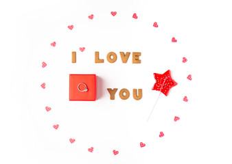 Valentine's day concept. Declaration of love, frame made of paper hearts, lollipop in form star. In the center red gift box with ring. Flat lay, top view, white background, isolated, copy space