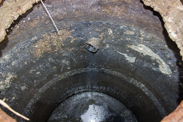 inside drainage pit,dangerously open drainage pit with dirt and black swamp with water