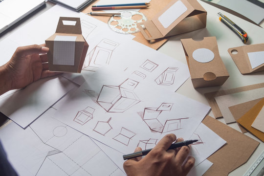 Designer sketching drawing design Brown craft cardboard paper product eco packaging mockup box development template package branding Label . designer studio concept .