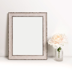 Picture frame standing on table with flower in decorative bottle, mock-up