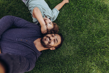 Father and son relaxing in a park lying on ground