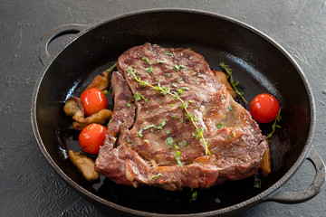 Restaurant cooking. Grilled meat in cast iron frying pan. Main course on black background.