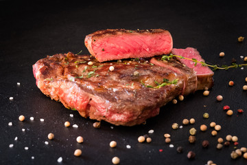 Meat cooking concept. Food composition. Rare steak and spices on black background.