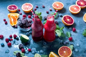 Berry smoothie with oranges and mint, healthy vitamin drink in bottles, refreshing juicy cocktail