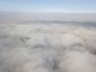 Aerial view of rural landscape in Switzerland covered with fog. Cold morning in winter with beautiful light. View from above the clouds with impressive sunlight.