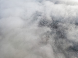 Obraz premium Aerial view of rural landscape in Switzerland covered with fog. Cold morning in winter with beautiful light. View from above the clouds with impressive sunlight.