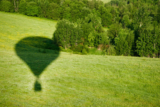 The shadow of the balloon on the background of a green meadow.