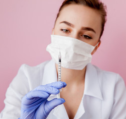 Close up nurse holding a syringe for injection, on pink background