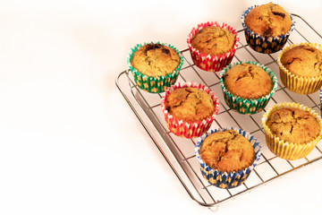 Banana chocolate chip muffins on wire rack, white background, with shallow depth of field.