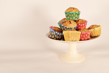 Banana chocolate chip muffins on cake plate, white background, with shallow depth of field and copy space.