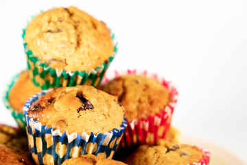 Banana chocolate chip muffins on white background, with shallow depth of field.