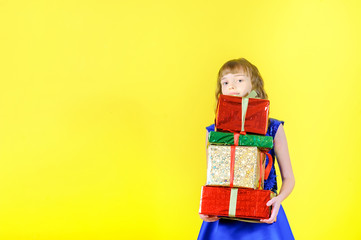 A girl in a dress holds many gifts in her hands, on a yellow background